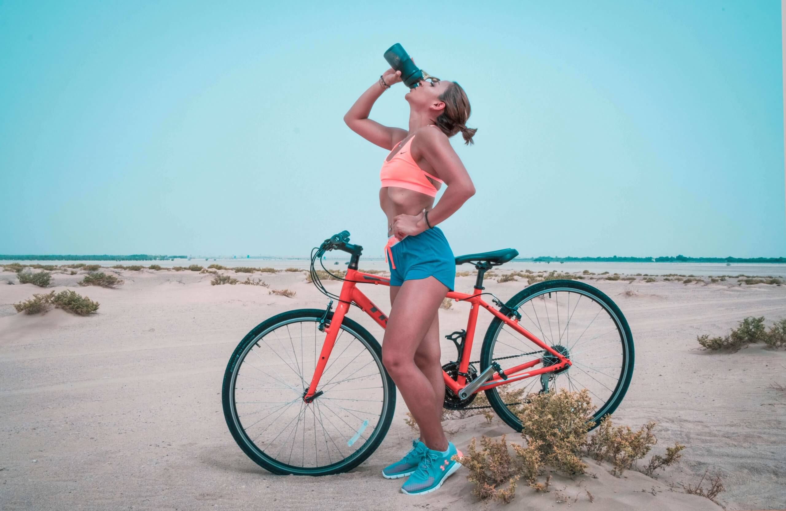 mulher ao lado de uma bicicleta a beber água